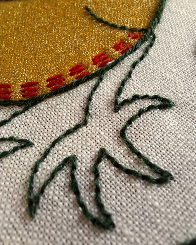 Gros plan sur une patte griffue du dragon. Brodée avec un simple contour vert foncé.