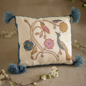 Coussin brodé dans un style pastel et médiéval : une branche de rosier avec 4 oiseaux perchés dessus.