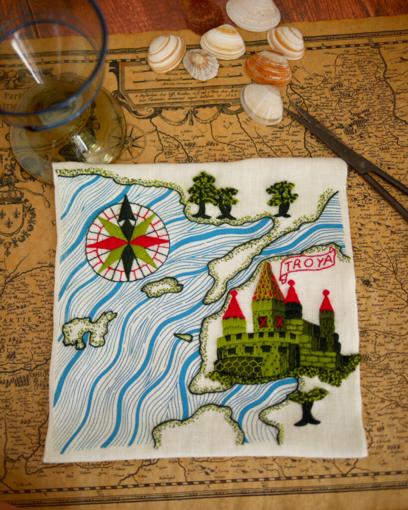 La même carte posée sur une carte ancienne avec des coquillages et un verre.