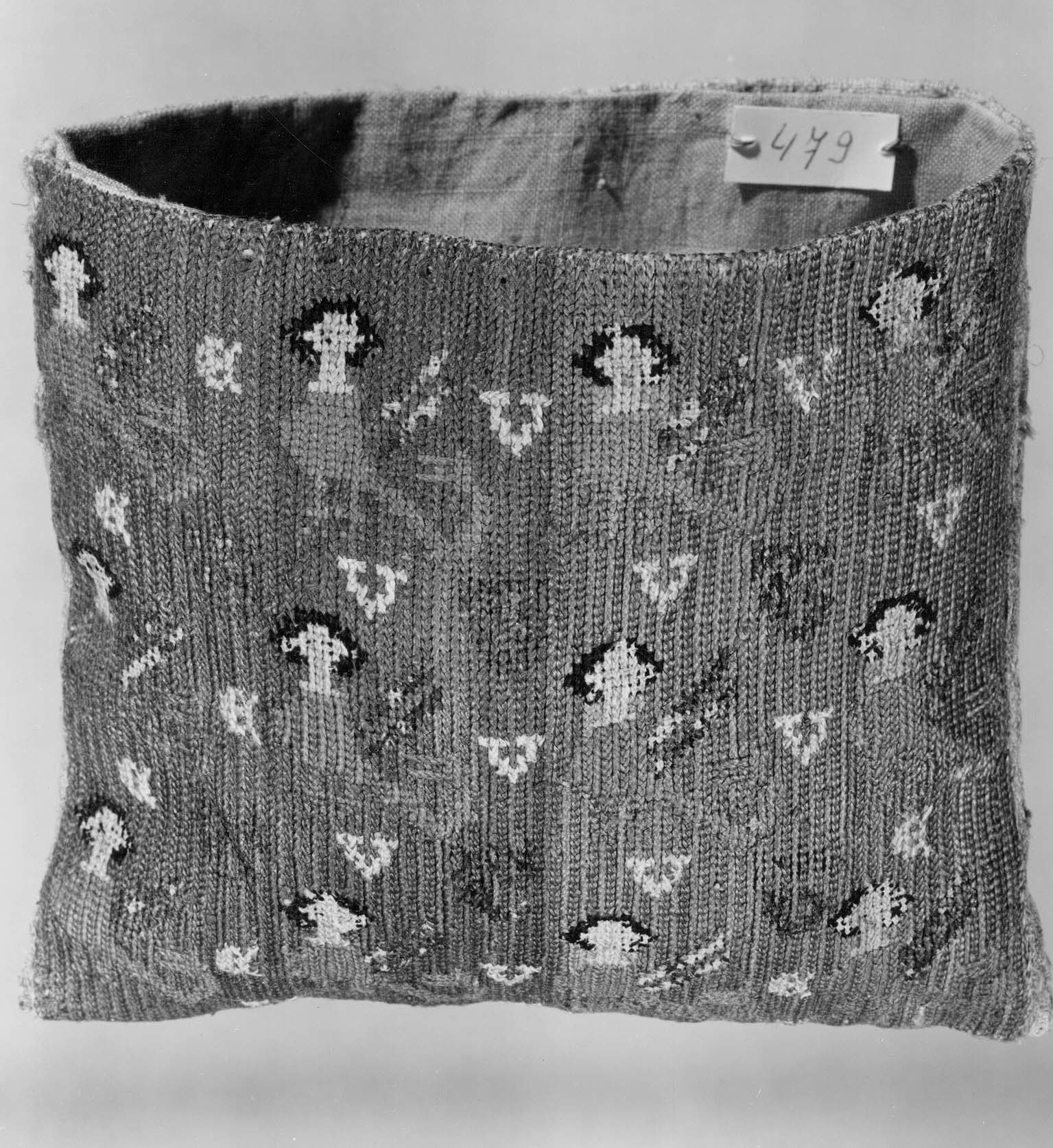 Une bourse médiévale brodée (photo en noir et blanc).
La broderie à points comptés, représente des sirène (oiseaux) alignées et stylisée (pixelisées). Les points forment des côtes verticales.