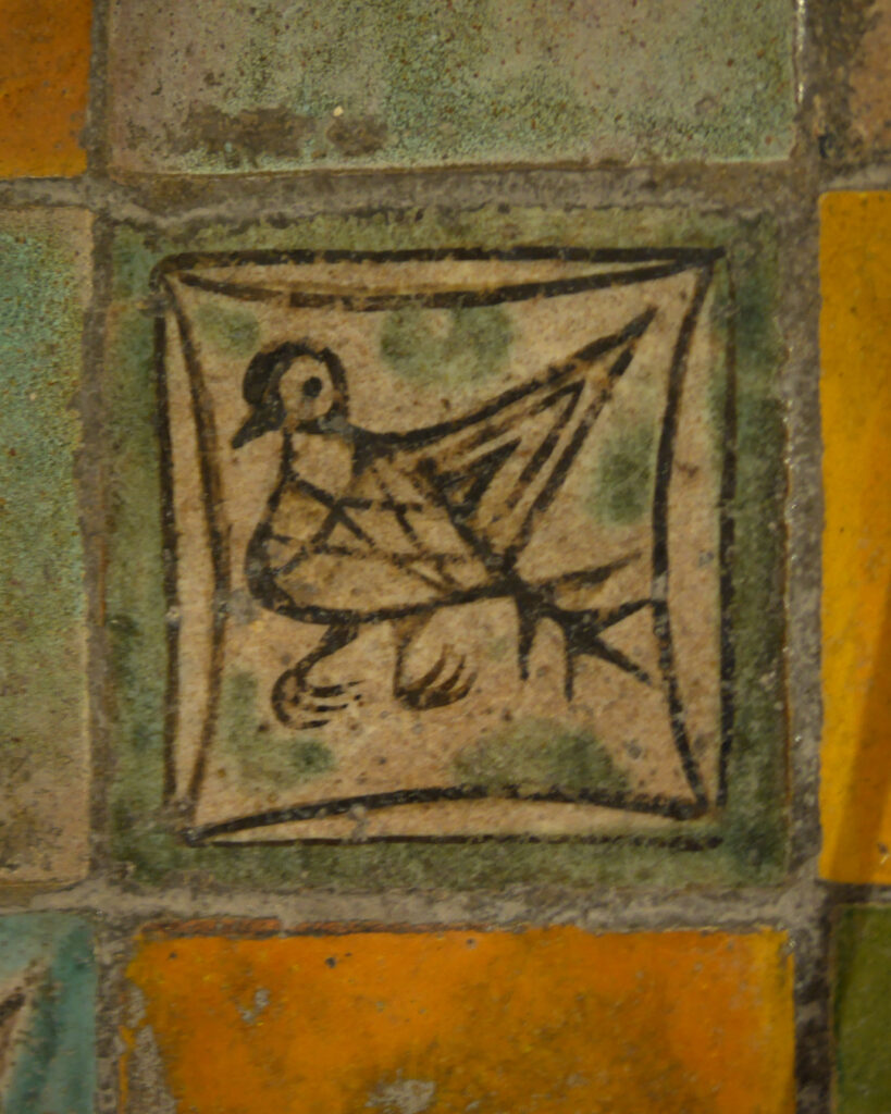 Carreau de pavement médiéval. Avec un contour vert, un petit oiseau noir.